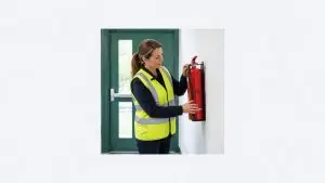 Fire marshal la locul de muncă verifică stingătorul de incendiu de lângă ieșirea de urgență