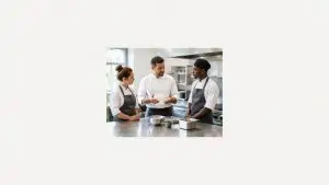 Training personal restaurant UK: un supervizor instruiește doi angajați în bucătăria unui restaurant